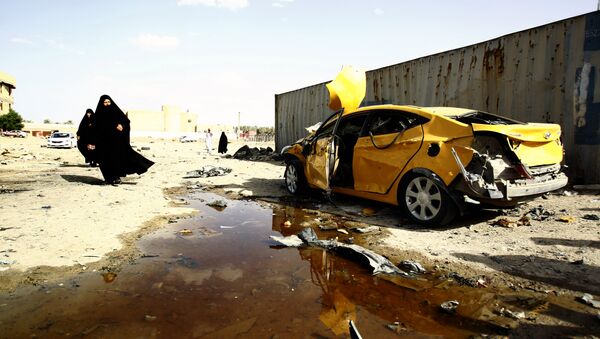 Iraqi women walk past a damaged car following a twin suicide bombing attack, claimed by the Islamic State (IS) group, in the southern Iraqi city of Samawah, situated deep in Iraq's Shiite heartland, on May 1, 2016 - Sputnik International