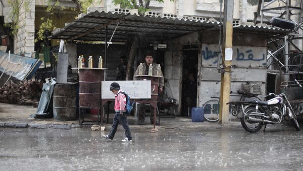A Syrian schoolboy walks under the rain in Kafr Batna, in the Eastern Ghouta area, on the outskirts of the capital Damascus (File) - Sputnik International