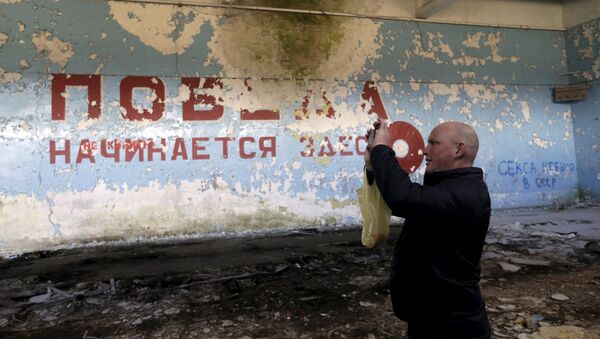 A man takes a picture inside sports hall in the ghost town of a former Soviet military radar station near Skrunda, Latvia, April 9, 2016. The words on the wall reads in Russian Victory starts here - Sputnik International