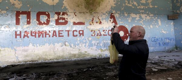 A man takes a picture inside sports hall in the ghost town of a former Soviet military radar station near Skrunda, Latvia, April 9, 2016. The words on the wall reads in Russian Victory starts here A man takes a picture inside sports hall in the ghost town of a former Soviet military radar station near Skrunda, Latvia, April 9, 2016. The words on the wall reads in Russian Victory starts here - Sputnik International