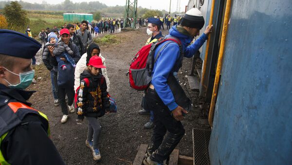 Migrants board a train after making their way through the countryside and crossing the Hungarian-Croatian border near the village of Zakany in Hungary to continue their trip to north on October 16, 2015 - Sputnik International
