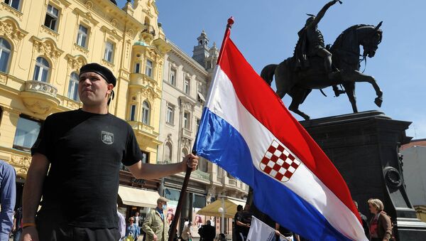 A man holds the Croatian flag as he takes part to a march in support of the Homeland War veterans' rights in Zagreb on April 14, 2015. Croatian leaders April 22, 2016, honoured the victims of the Balkan country's most notorious World War II death camp, in an event boycotted by critics who accuse rulers of tolerating a revival of pro-Nazi ideology - Sputnik International