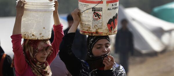 Syrian refugee girls carry over their heads buckets of water as they walk at Atmeh refugee camp, in the northern Syrian province of Idlib, Syria Syrian refugee girls carry over their heads buckets of water as they walk at Atmeh refugee camp, in the northern Syrian province of Idlib, Syria - Sputnik International