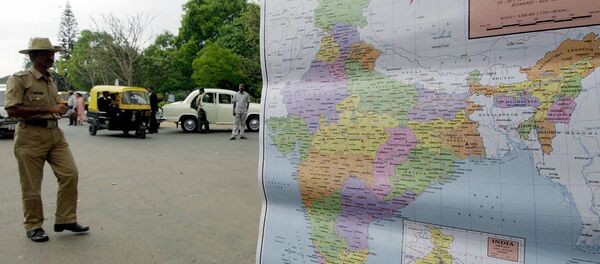 Unemployed Indian youth Sanjay Singh (R) waits for customers to buy his maps of India in Bangalore, as a police officer (L) walks by. Unemployed Indian youth Sanjay Singh (R) waits for customers to buy his maps of India in Bangalore, as a police officer (L) walks by. - Sputnik International
