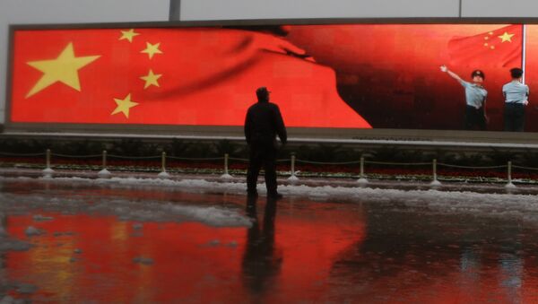 Chinese man stands near a screen displaying the Chinese national flag - Sputnik International
