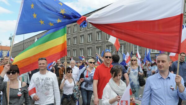 Opponents of Poland's government carry a Polish and EU flags tied together as they march downtown streets to protest the country's direction under a conservative government that is accused of eroding the rule of law, in Warsaw, Poland, Saturday, May 7, 2016. - Sputnik International