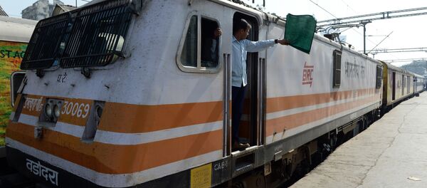 In this photograph taken on December 9, 2015, an Indian locomotive driver of the Ahmedabad bound Karnavati Express waves a green flag as he signals the depature of the train from Mumbai Central railway station in Mumbai In this photograph taken on December 9, 2015, an Indian locomotive driver of the Ahmedabad bound Karnavati Express waves a green flag as he signals the depature of the train from Mumbai Central railway station in Mumbai - Sputnik International