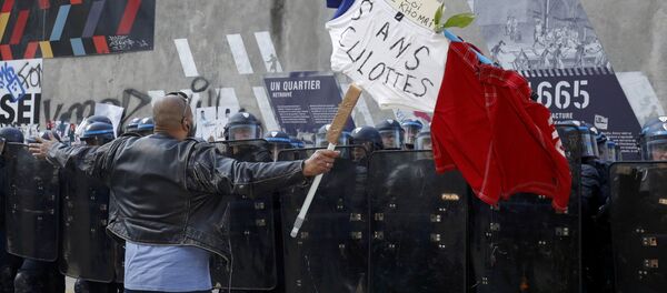 A man holds a French flag with the message, No to the El Khomri law in front of a line of French riot police during a protest against the French labour law proposal during the May Day labour union march in Paris, France, May 1, 2016. A man holds a French flag with the message, No to the El Khomri law in front of a line of French riot police during a protest against the French labour law proposal during the May Day labour union march in Paris, France, May 1, 2016. - Sputnik International