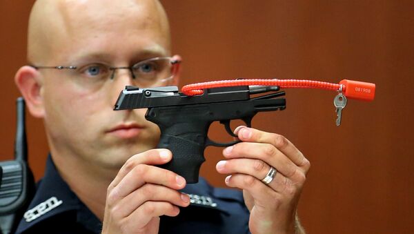 In this June 28, 2013, file photo, Sanford police officer Timothy Smith holds up the gun that was used to kill Trayvon Martin. - Sputnik International