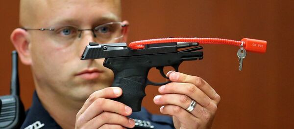 In this June 28, 2013, file photo, Sanford police officer Timothy Smith holds up the gun that was used to kill Trayvon Martin. - Sputnik International