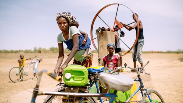 Barry Aliman, 24 years old, bicycles with her baby to fetch water for her family, Sorobouly village near Boromo, Burkina Faso. - Sputnik International