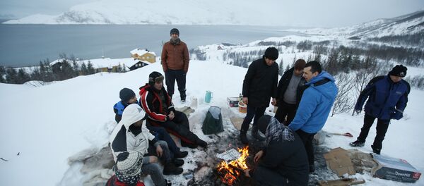 Asylum seekers gather round a fire as they cook a meal overlooking the temporary Altnes camp refugee camp on the island of Seiland, northern Norway (File) Asylum seekers gather round a fire as they cook a meal overlooking the temporary Altnes camp refugee camp on the island of Seiland, northern Norway (File) - Sputnik International