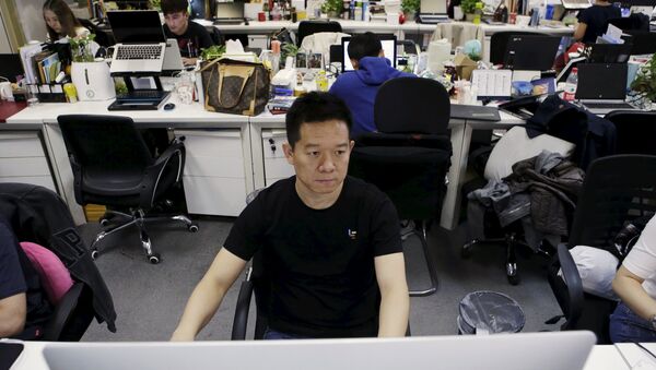 Jia Yueting, co-founder and head of Le Holdings Co Ltd, also known as LeEco and formerly as LeTV, uses a computer on a staff's seat as he poses for a photo (File) - Sputnik International