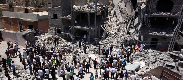 Libyans gather  next to the rubble of buildings the Libyan authorities said were damaged by airstrikes on Tripoli's residential district of Arada (File) - Sputnik International