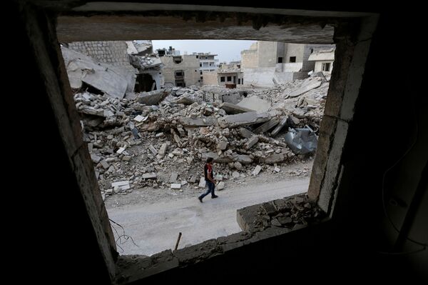 A man walks past damaged buildings in the rebel-controlled area of Maaret al-Numan town in Idlib province, Syria, May 15, 2016 - Sputnik International