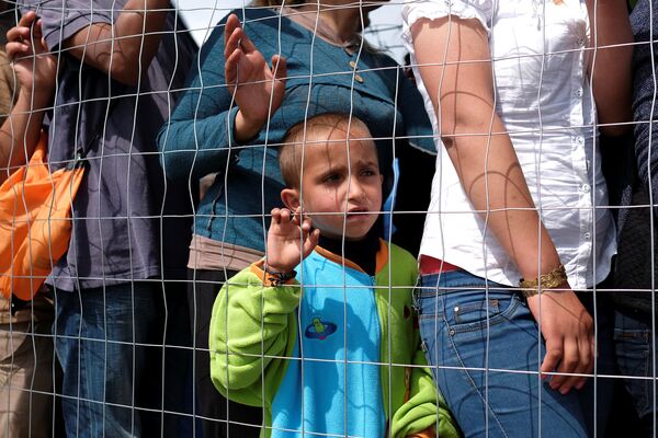 A boy queues for free food at a makeshift camp for migrants and refugees at the Greek-Macedonian border near the village of Idomeni, Greece, May 11, 2016. A boy queues for free food at a makeshift camp for migrants and refugees at the Greek-Macedonian border near the village of Idomeni, Greece, May 11, 2016. - Sputnik International