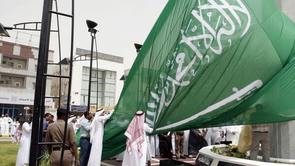 Saudi men unfurl a giant Saudi national flag during a ceremony to raise the highest flag in the country in the eastern city of Dammam on June 17, 2008 - Sputnik International