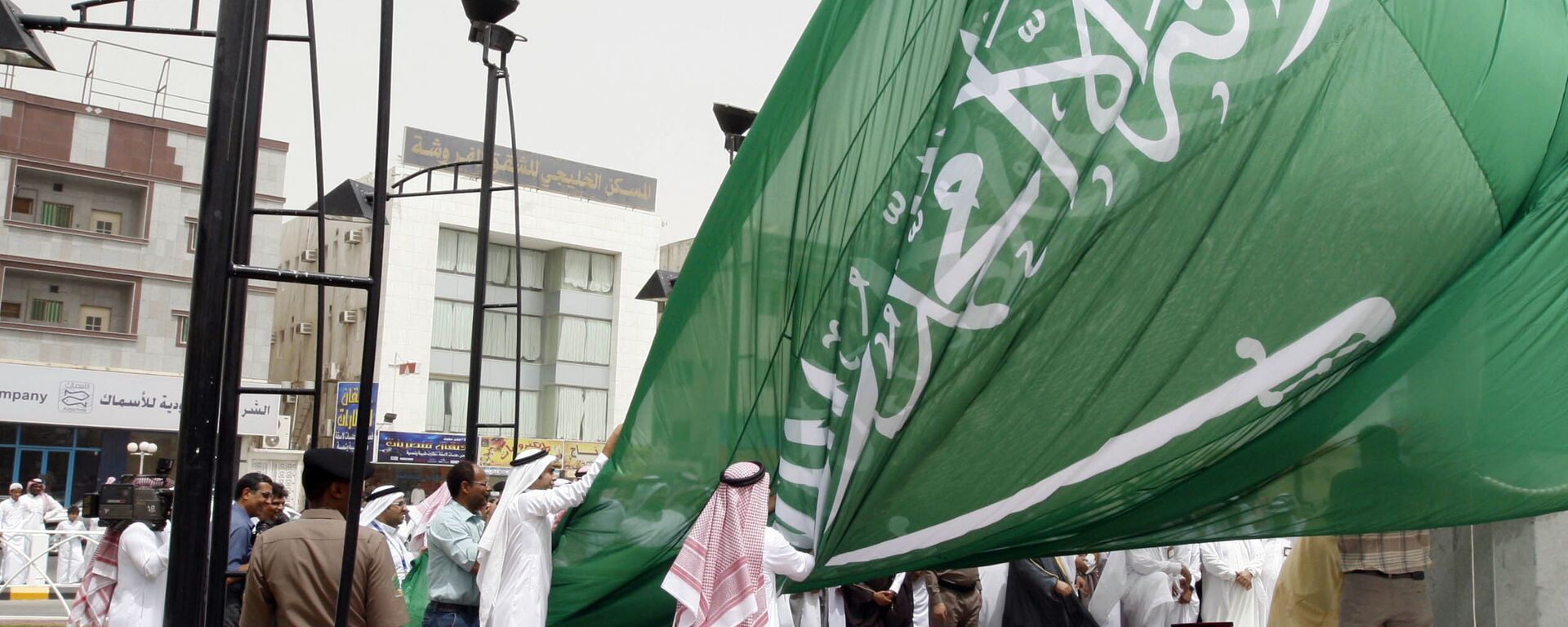 Saudi men unfurl a giant Saudi national flag during a ceremony to raise the highest flag in the country in the eastern city of Dammam on June 17, 2008 - Sputnik International, 1920, 02.06.2024