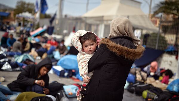 A Syrian woman holds her child at the port of Chios on April 3, 2016 as refugees and migrants who broke out from Chios detention camp, stand in the port of the city. - Sputnik International