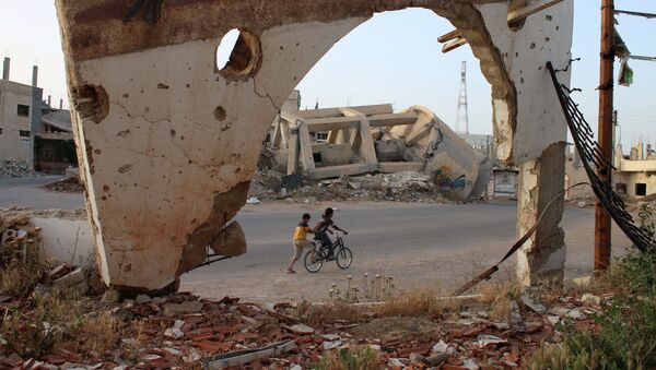 A picture taken through an arch remaining from a detroyed building shows Syrian boys on a bicycle on May 14, 2016 in the southern Syrian city of Daraa.  - Sputnik International