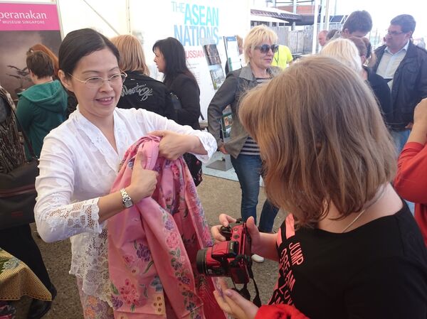 Karen Chin is helping Anna, a tourist from Murmansk to try on the rare folk costume. - Sputnik International
