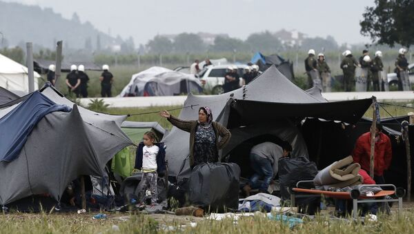 A migrant family stands outside their tent during an evacuation operation by police forces of a makeshift migrant camp at the border at the Greek-Macedonian border near the village of Idomeni, on May 24, 2016 - Sputnik International