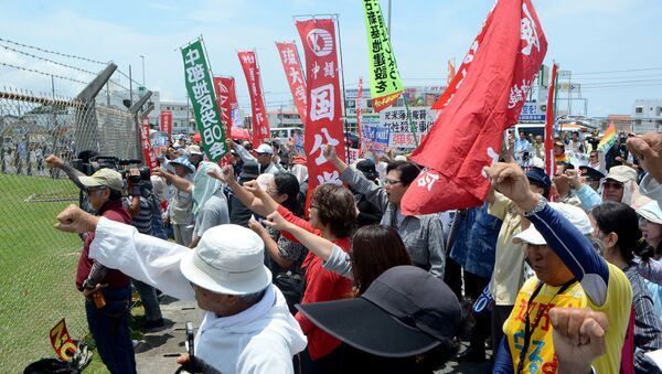 People raise their fists as they shout slogans to protest against the US military presence in front of the US Kadena Air Base in Cyatan, Okinawa prefecture, on May 21, 2016 - Sputnik International