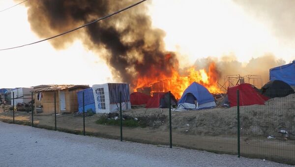 Smoke rises from the huts and tents set on fire during clashes between migrants, at a makeshift camp, in Calais, France, Thursday, May 26, 2016 - Sputnik International