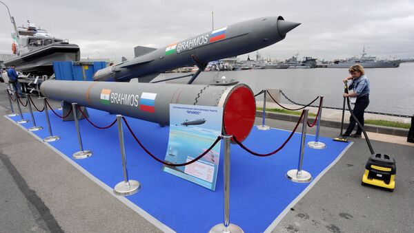 A woman cleans a carpet flooring close to a Brahmos supersonic cruise missile at the International Maritime Defence Show in St. Petersburg on July 2, 2015. - Sputnik International