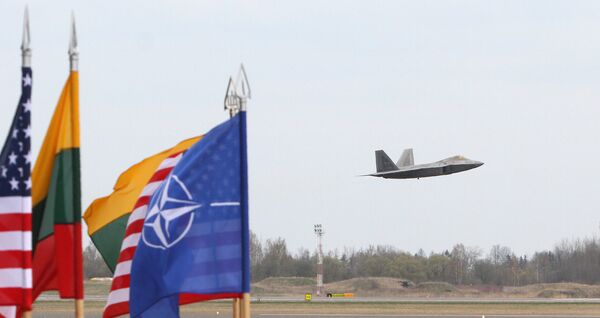 A US Air Force F-22 Raptor fighter aircraft flies at the Air Base of the Lithuanian Armed Forces in Šiauliai, Lithuania, on April 27, 2016 behind flags of US, Lithiania and the NATO - Sputnik International