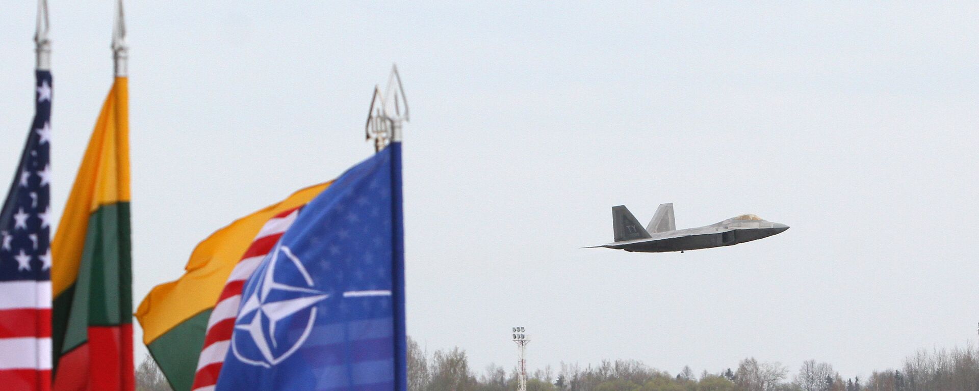 A US Air Force F-22 Raptor fighter aircraft flies at the Air Base of the Lithuanian Armed Forces in Šiauliai, Lithuania, on April 27, 2016 behind flags of US, Lithiania and the NATO - Sputnik International, 1920, 13.07.2022