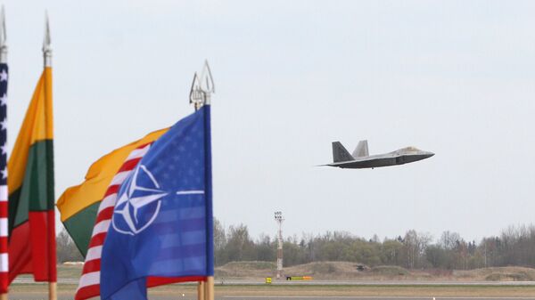 A US Air Force F-22 Raptor fighter aircraft flies at the Air Base of the Lithuanian Armed Forces in Šiauliai, Lithuania, on April 27, 2016 behind flags of US, Lithiania and the NATO - Sputnik International