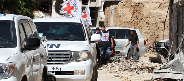 Vehicles of the International Committee of the Red Cross (ICRC) and the United Nations wait on a street after an aid convoy entered the rebel-held Syrian town of Daraya, southwest of the capital Damascus, on June 1, 2016 - Sputnik International