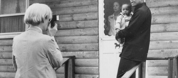 Pop artist Andy Warhol, left, is shown photographing Muhammad Ali, his infant daughter, Hanna, and wife, Veronica, Thursday, August 18, 1977, at Ali's training camp in Deer Lake, Pa. Pop artist Andy Warhol, left, is shown photographing Muhammad Ali, his infant daughter, Hanna, and wife, Veronica, Thursday, August 18, 1977, at Ali's training camp in Deer Lake, Pa. - Sputnik International