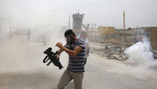Palestinian journalists run for cover from tear gas canisters fired by Israeli forces during a demonstration in support of Palestinian journalists on the occasion of the World Press Freedom day outside the compound of the Israeli-run Ofer prison near Betunia in the occupied West Bank, on May 3, 2016 - Sputnik International