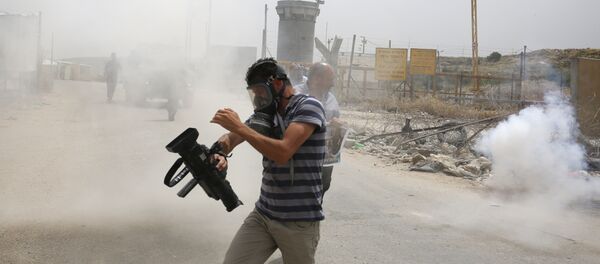 Palestinian journalists run for cover from tear gas canisters fired by Israeli forces during a demonstration in support of Palestinian journalists on the occasion of the World Press Freedom day outside the compound of the Israeli-run Ofer prison near Betunia in the occupied West Bank, on May 3, 2016 - Sputnik International
