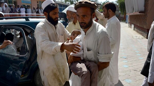 An Afghan volunteer carries a wounded child following an explosion inside a mosque in the Rodat district of Nangarhar province on June 10, 2016 - Sputnik International