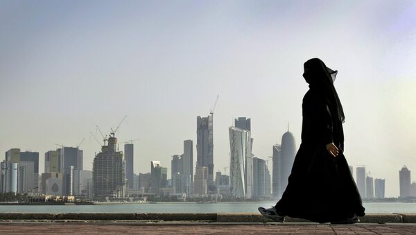 A Qatari woman walks in front of the city skyline in Doha, Qatar. File photo - Sputnik International