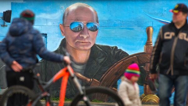Pedestrians near a portrait of Russian President Vladimir Putin on a wall of a building in Yalta - Sputnik International