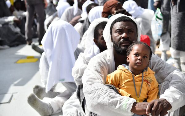 A man and his daughter wait during a distribution of meals aboard the rescue ship Aquarius, on May 25, 2016 a day after a rescue operation of migrants and refugees off the Libyan coast. - Sputnik International