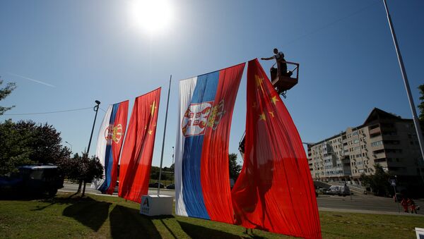 A worker adjusts Chinese and Serbian flags for the upcoming visit of Chinese President Xi Jinping - Sputnik International
