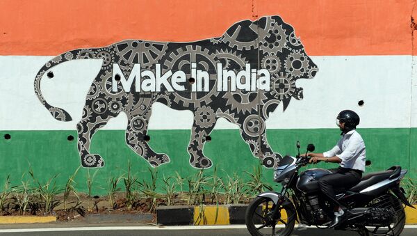 This file photograph taken on February 12, 2016 shows an Indian motorist riding past a wall bearing the image of the mascot for 'Make in India Week' in Mumbai - Sputnik International