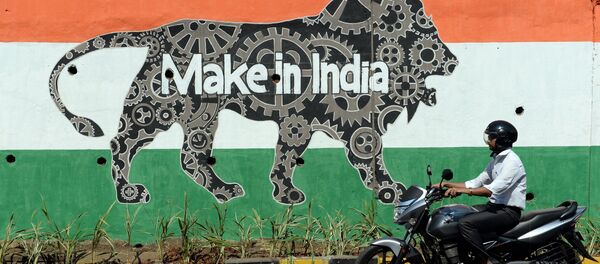 This file photograph taken on February 12, 2016 shows an Indian motorist riding past a wall bearing the image of the mascot for 'Make in India Week' in Mumbai - Sputnik International