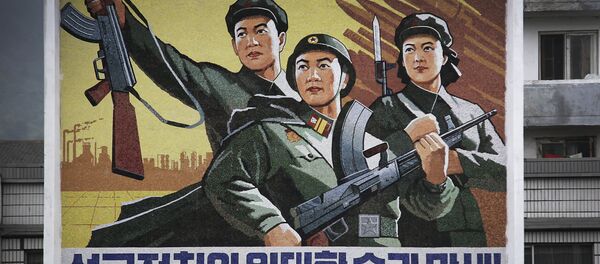 A North Korean man and woman walk under a mural with a message which reads Long live the great victory of the army-first policy in the city center of Wonsan on Wednesday, June 22, 2016, in Wonsan, North Korea. - Sputnik International