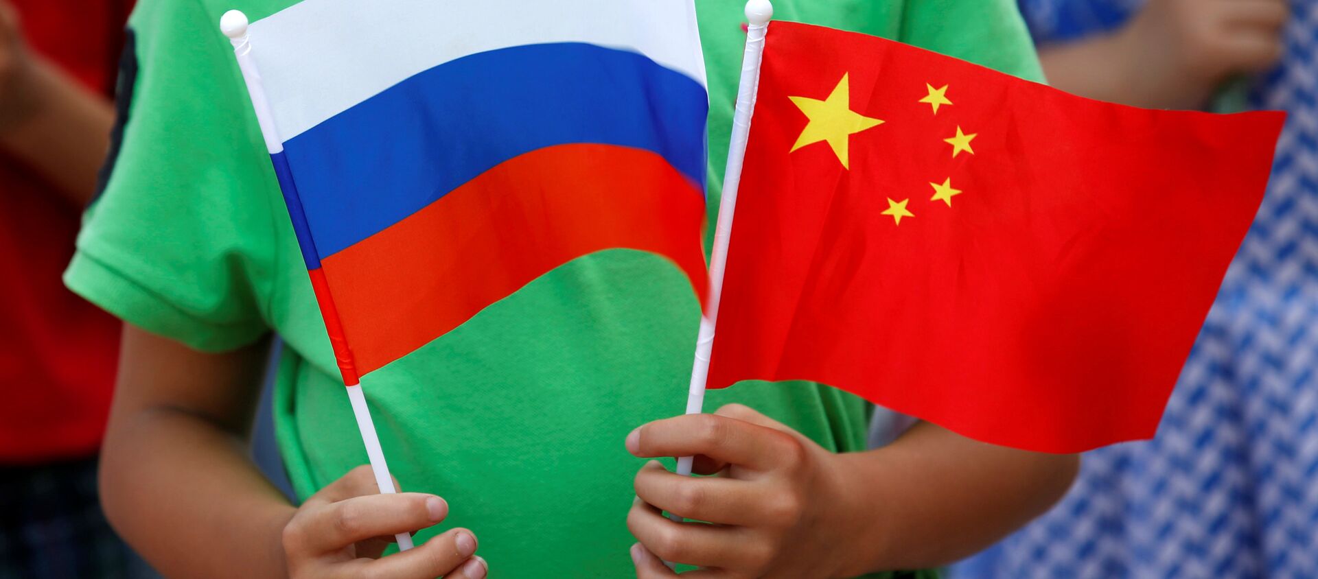 A child holds the national flags of Russia and China prior to a welcoming ceremony for Russian President Vladimir Putin outside the Great Hall of the People in Beijing, China, June 25, 2016 - Sputnik International, 1920, 11.09.2018
