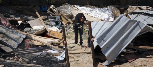 A woman from the Arab Jahalin Bedouin community carries a mirror after the demolition of her home in the West Bank Bedouin camp of al-Khan al-Ahmar on April 7, 2016 - Sputnik International