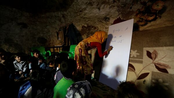 A teacher conducts a lesson for internally displaced children inside a cave in the rebel-controlled village of Tramla, in Idlib province, Syria March 27, 2016 - Sputnik International