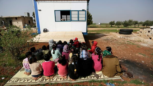 Children watch as volunteer teachers perform a puppet show inside a mobile educational caravan for children who do not have access to schools on the outskirts of the Syrian rebel-held town of Saraqib, Idlib province March 10, 2016 - Sputnik International