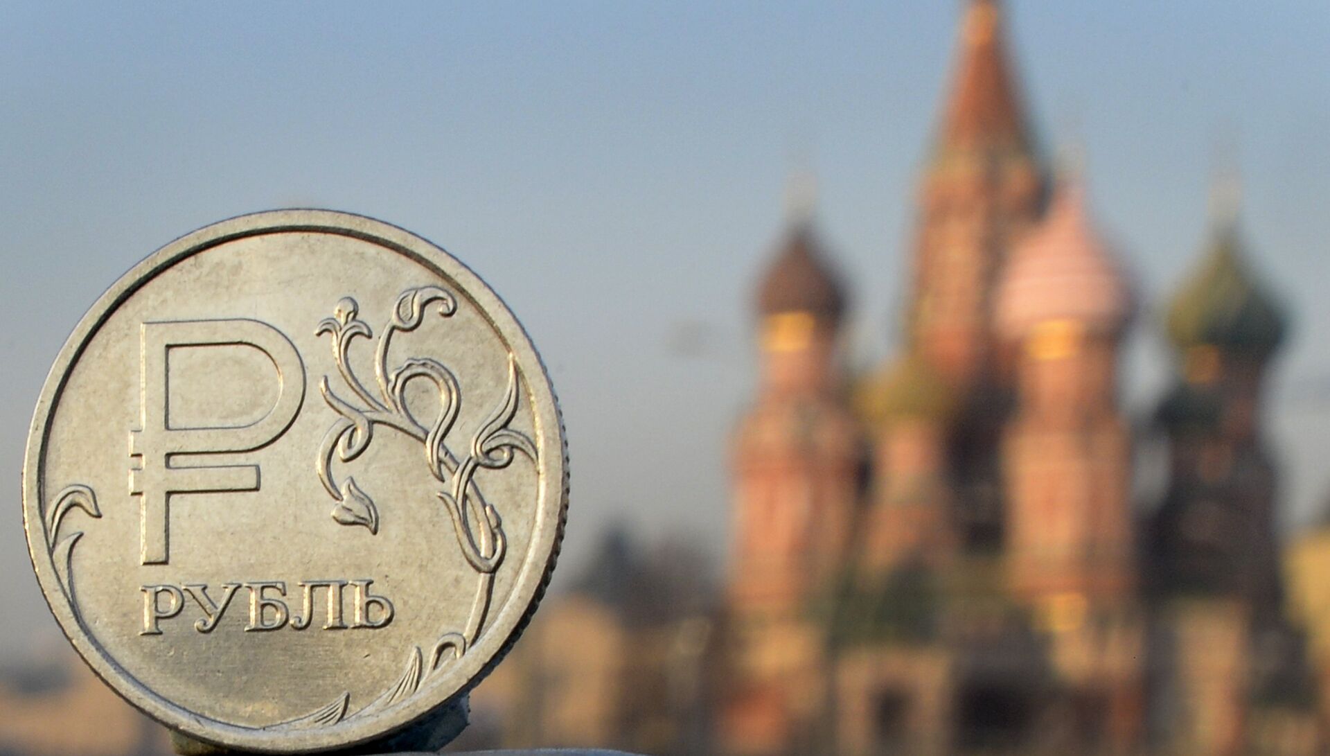 A Russian ruble coin is pictured in front of St. Basil cathedral in central Moscow - Sputnik International, 1920, 29.11.2022