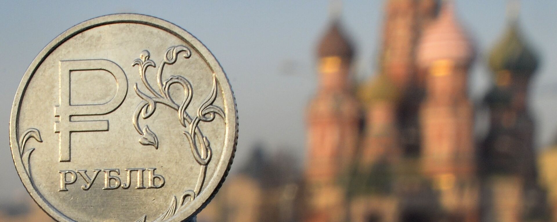 A Russian ruble coin is pictured in front of St. Basil cathedral in central Moscow - Sputnik International, 1920, 19.07.2023